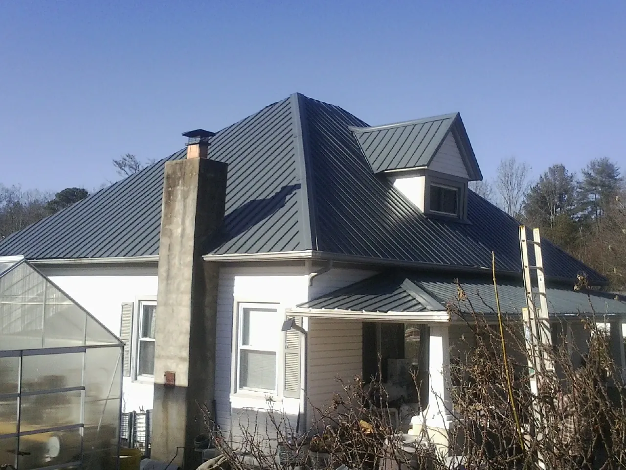Dark blue standing seam metal roof on a white farmhouse with dormer — Slate & Tile Roof Repair by Roofing Brothers in North Berwick