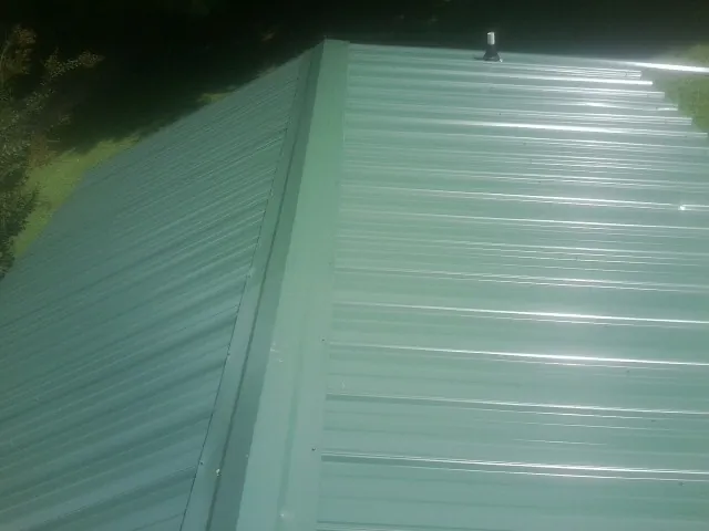 New green metal panels meeting at the ridge of a roof — Flat Roof Repair work by our crew in North Berwick