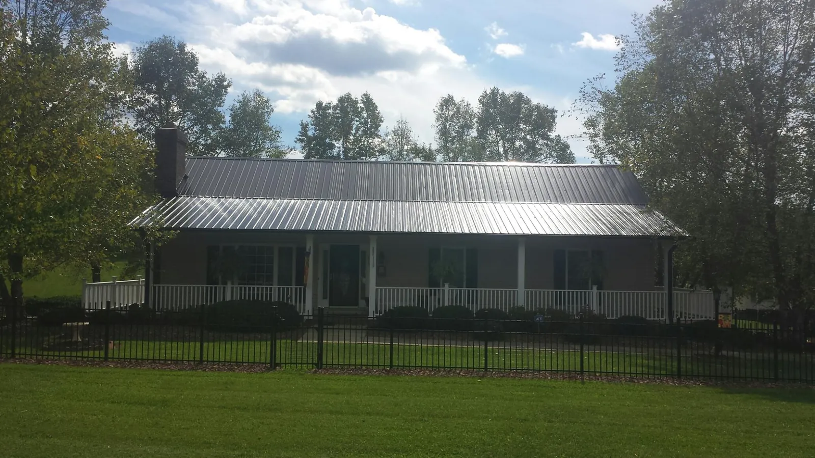 Gray metal roof on a brick ranch with a full width front porch — Gutter Guard Installation work by our crew in North Berwick