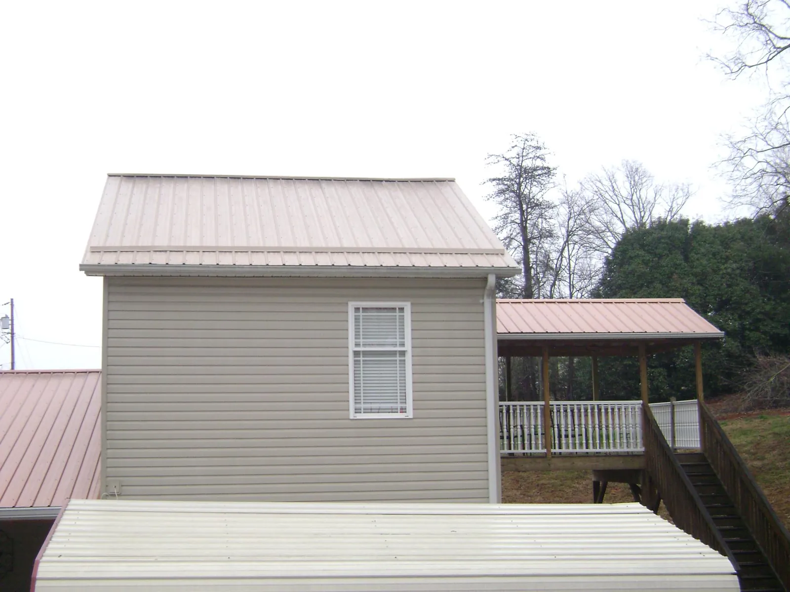 Tan metal roofs on a two story addition and attached porch, from a Roof Replacement job in North Berwick