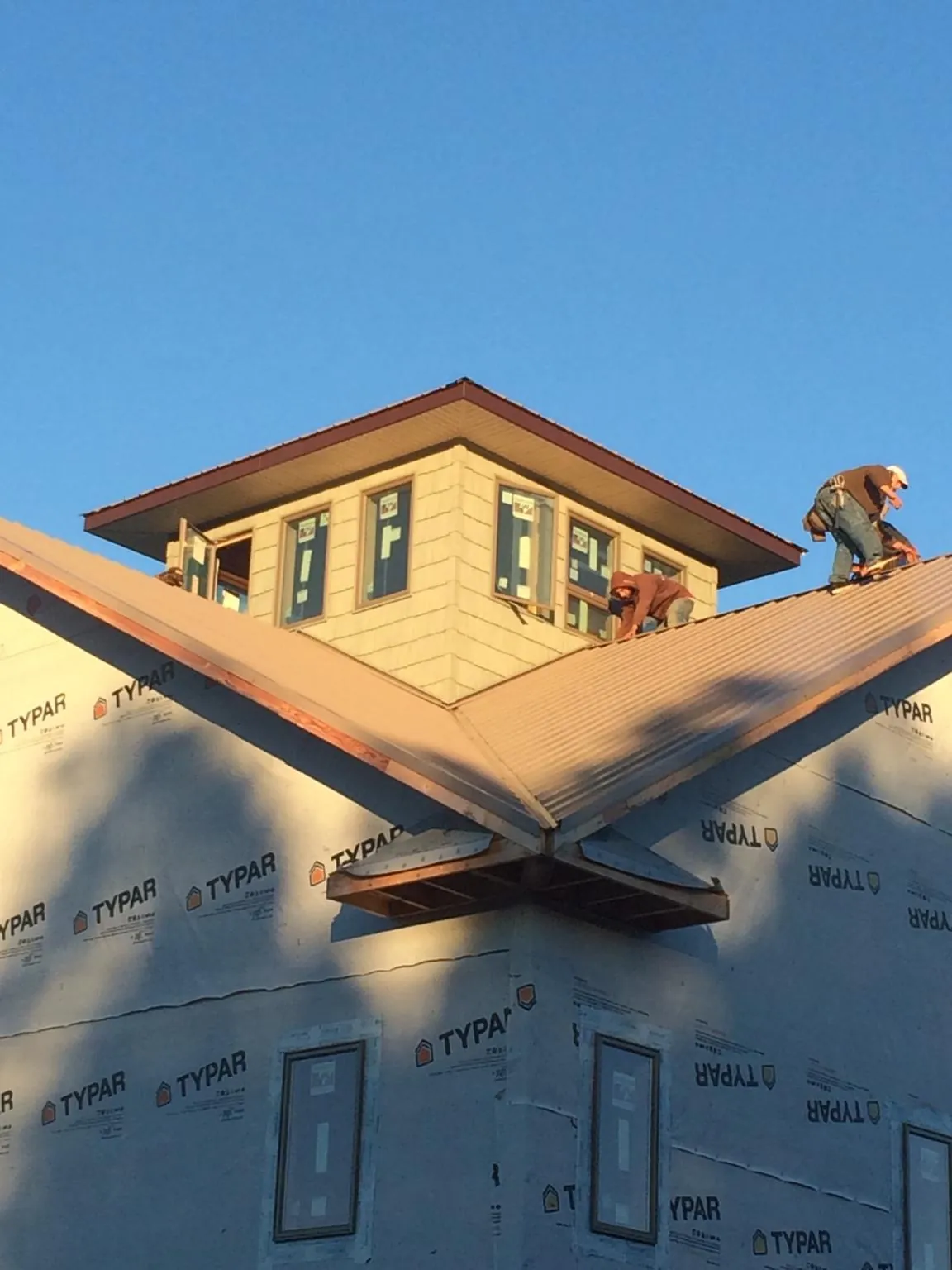 Roofers working around a rooftop cupola on a new metal roof at sunset — Roof Waterproofing in North Berwick by Roofing Brothers